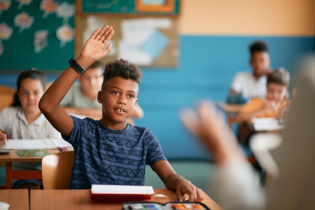 A student raising their hand in a classroom